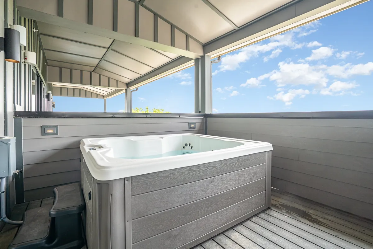 A rooftop deck with a hot tub, wooden decking, and expansive sky views, inviting groups to unwind and socialize while soaking up the Nashville skyline. The setting is tranquil yet perfect for group celebrations or relaxing after exploring the city.