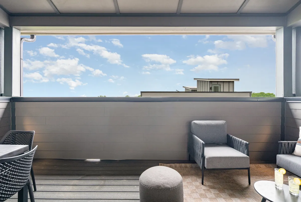 A serene rooftop or upper-level outdoor seating area set against a sky view, with decorative elements on the table. The space is arranged for small gatherings, relaxation, and enjoying drinks or conversations while overlooking the cityscape.
