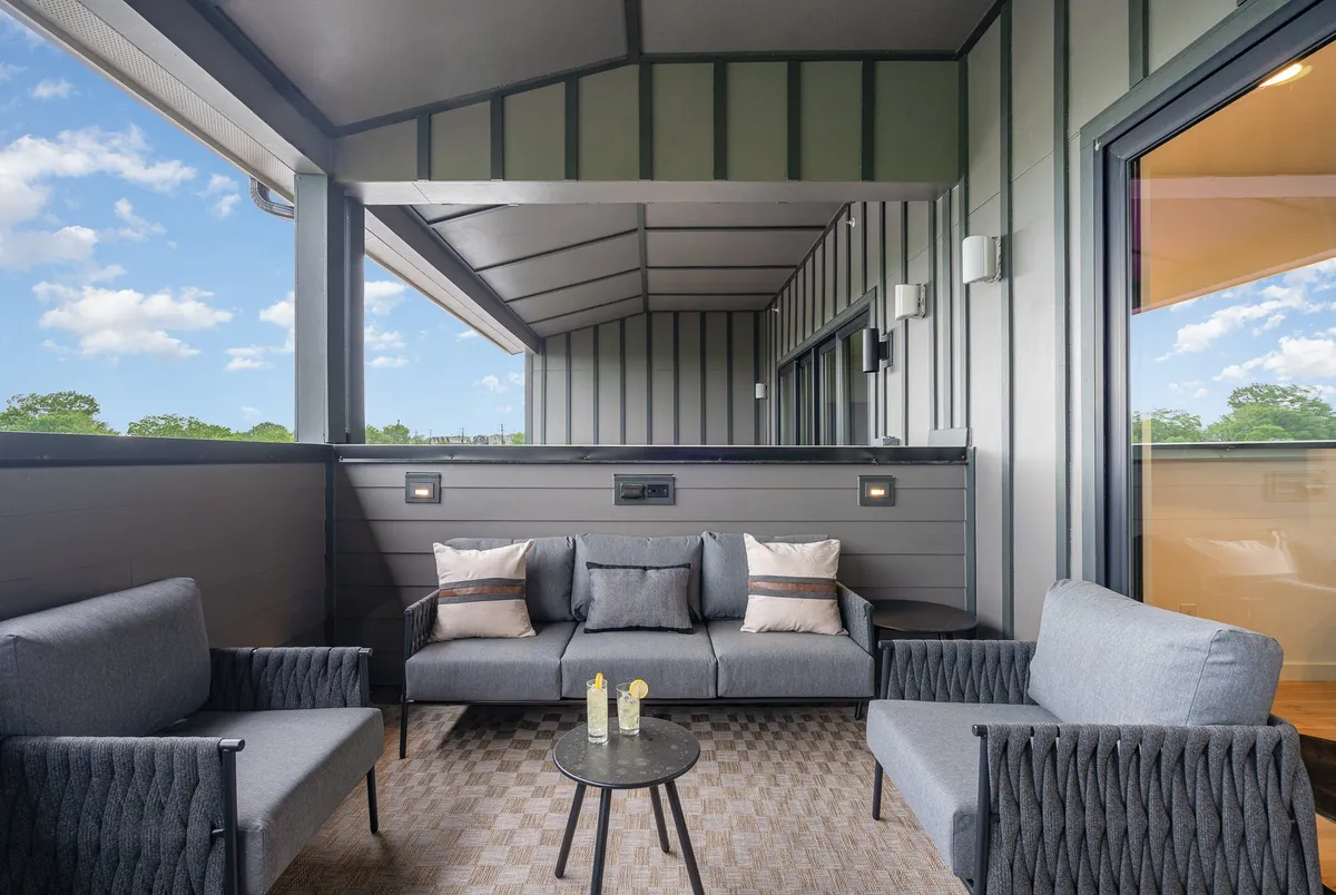A tranquil and welcoming exterior seating nook, styled with cozy cushions and a small table, set for intimate gatherings or quiet moments. Its design suggests a comfortable spot to unwind after a big night out.